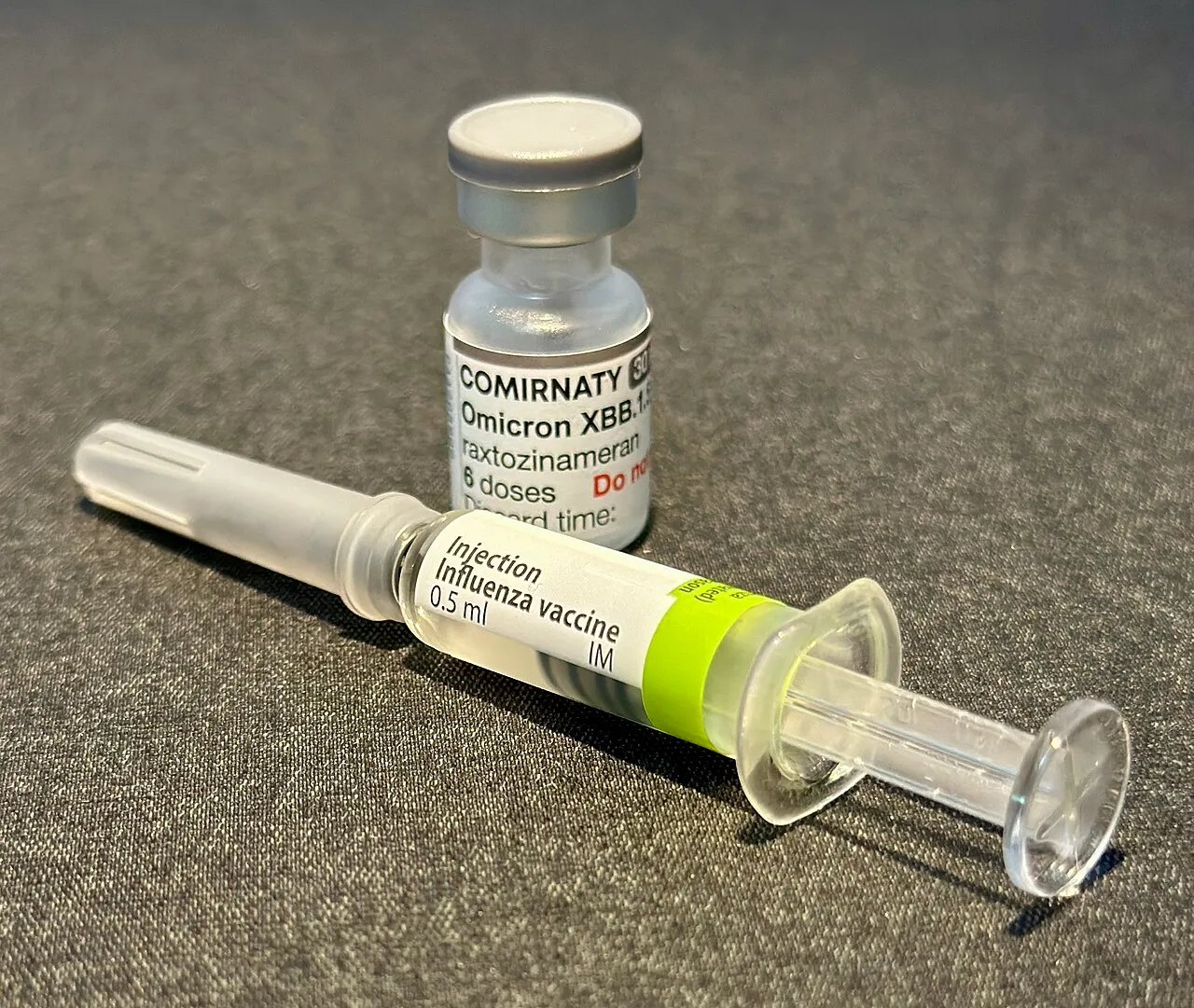 Een flacon griepvaccin naast een voorgevulde spuit, gebruikt voor de jaarlijkse griepvaccinatie
